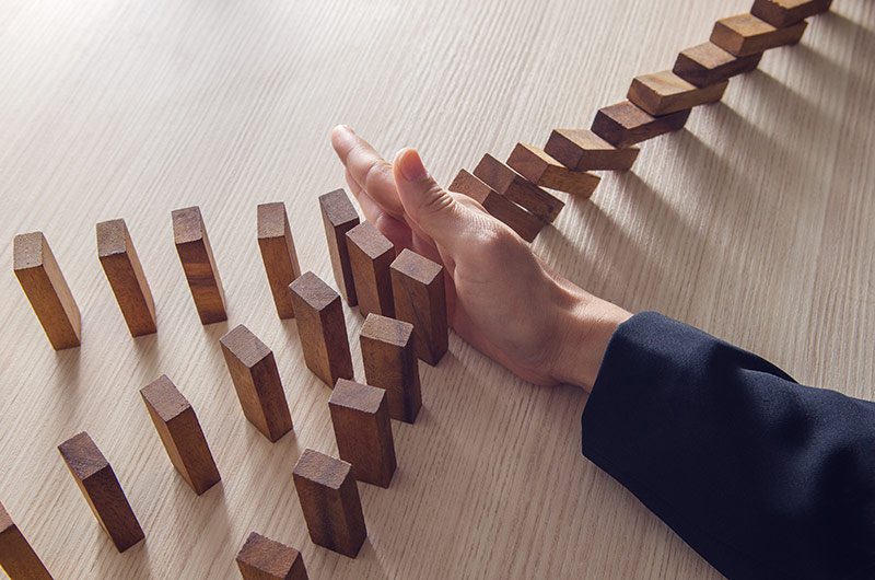 Businesswoman hand stopping domino wooden effect